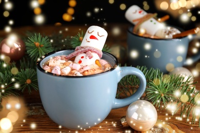 Marshmallow snowman in cup with hot drink on wooden table. Bokeh effect 