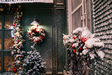 Beautiful decorative garland covered with snow near window outdoors. Christmas celebration