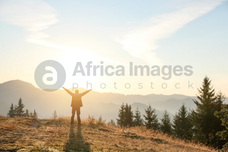 Photo of Man enjoying sunrise in mountains, back view. Space for text