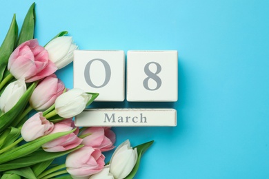 Wooden block calendar with date 8th of March and tulips on light blue background, flat lay. Space for text