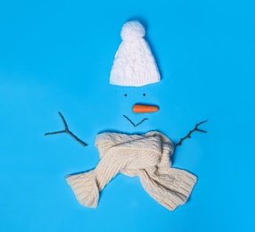 Creative snowman shape made of different items on light blue background, flat lay