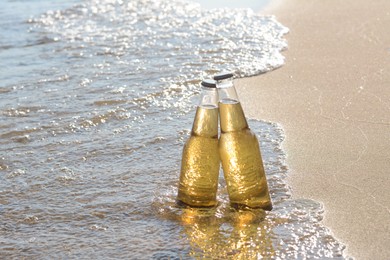 Bottles of cold beer in sea water on sunny day