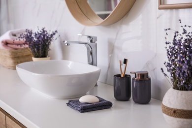 Bathroom counter with vessel sink, accessories and flowers. Interior design
