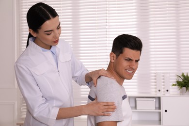 Doctor examining man with shoulder pain in hospital
