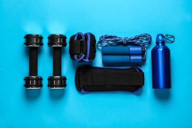 Weighting agents and sport equipment on light blue background, flat lay