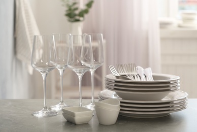 Set of clean dishware, cutlery and wineglasses on grey table indoors