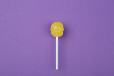 Tasty lemon lollipop on purple background, top view