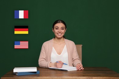Portrait of foreign languages teacher at wooden table and different flags green chalkboard