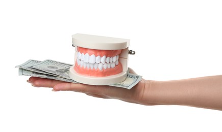 Woman holding educational dental typodont model and dollar banknotes on white background, closeup. Expensive treatment