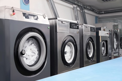 Row of modern washing machines in dry-cleaning