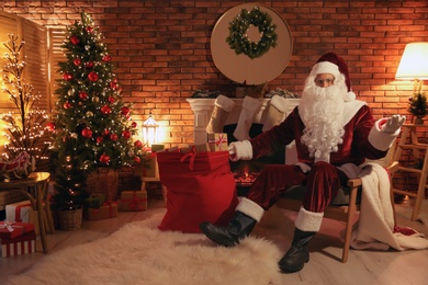 Santa Claus with sack of gifts in armchair at home