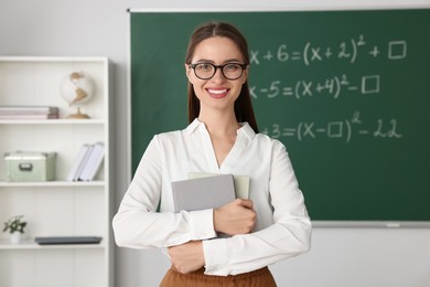 Photo of Portrait of young math’s teacher near chalkboard in classroom