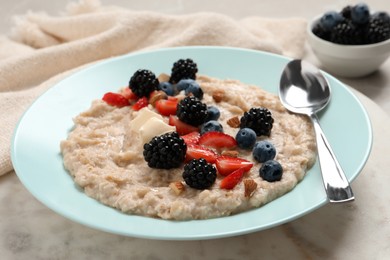 Tasty oatmeal porridge with berries and almond nuts in plate on table
