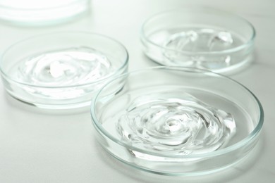 Photo of Petri dishes with liquids on white marble table, closeup