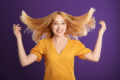 Beautiful young woman with blonde hair on purple background