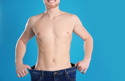 Young man in oversized jeans on color background, closeup