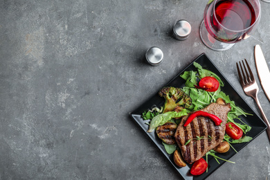Delicious beef steak served on grey table, flat lay. Space for text