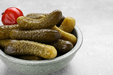 Bowl of pickled cucumbers and pepper on light grey table, closeup