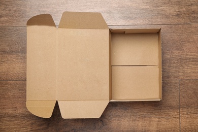 Open cardboard box on wooden background, top view