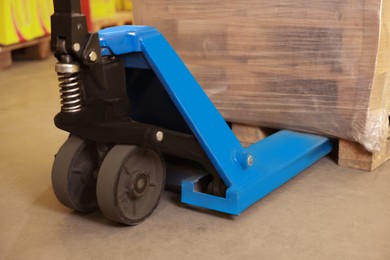 Manual forklift with wrapped pallets in warehouse, closeup. Logistics concept