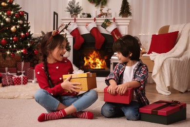 Happy children with Christmas gift boxes on floor at home