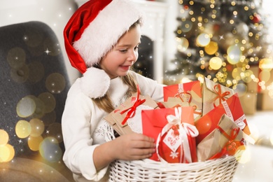 Image of Cute little girl in Santa hat with gifts from Christmas advent calendar at home. Bokeh effect