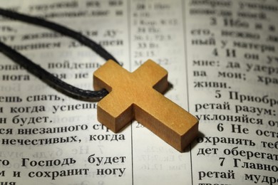 MYKOLAIV, UKRAINE - DECEMBER 21, 2021: Wooden cross on Bible, closeup. Text in russian