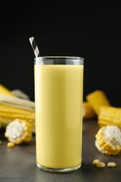 Freshly made corn juice in glass on grey table against black background