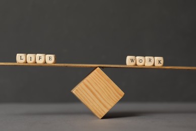 Wooden scale with words Life, Work made of cubes on grey background. Balance concept