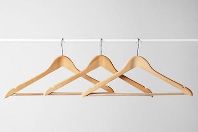 Photo of Wooden clothes hangers on metal rail against light grey background