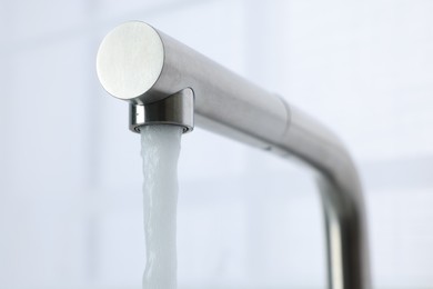Photo of Stream of water flowing from tap on white background, closeup