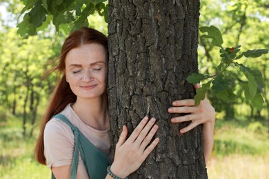 Beautiful woman hugging tree trunk in forest
