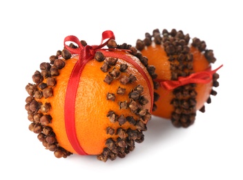 Pomander balls with red ribbons made of fresh tangerines and cloves on white background