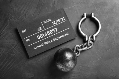 Metal ball with chain and mugshot letter board on grey table, flat lay