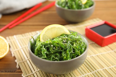 Japanese seaweed salad with lemon slice served on table, closeup