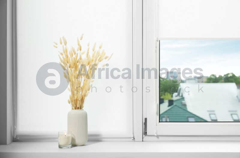 Photo of Window with blinds and dry plants on sill indoors