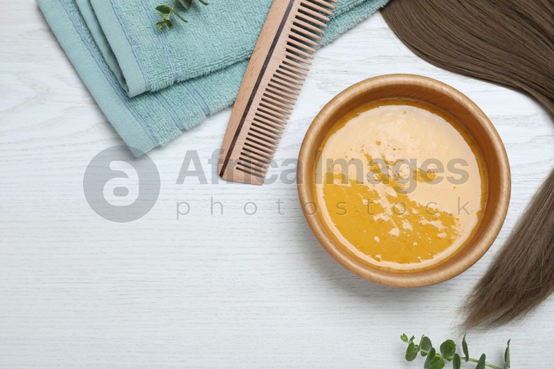 Flat lay composition with homemade hair mask in bowl on white wooden table, space for text