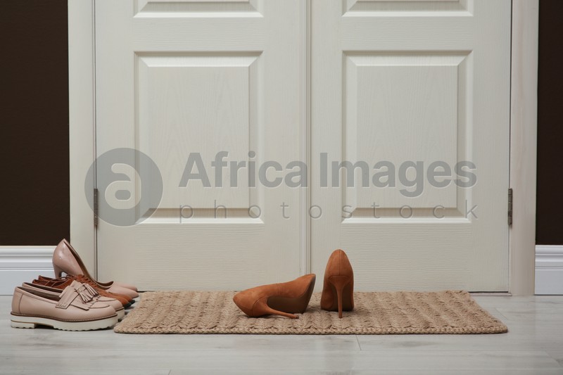 Stylish shoes and door mat in hall