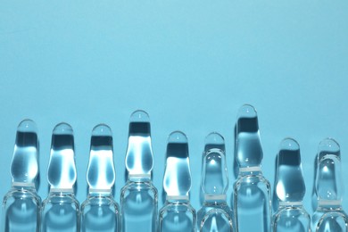 Pharmaceutical ampoules with medication on light blue background, flat lay. Space for text