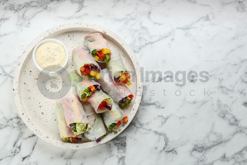 Delicious rolls wrapped in rice paper served on marble table, top view. Space for text