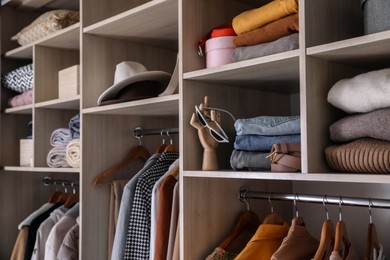Wardrobe closet with different stylish clothes, accessories and home stuff