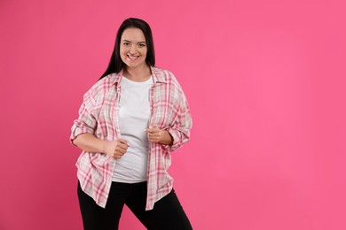 Beautiful overweight woman with charming smile on pink background. Space for text