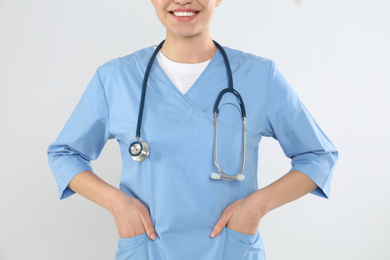 Young doctor with stethoscope on light background, closeup