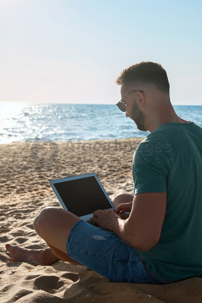 Man working with modern laptop on beach