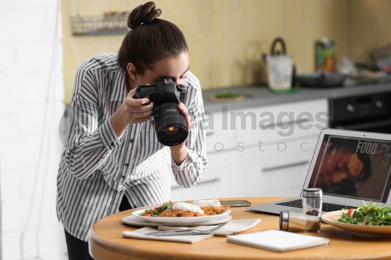 Photo of Food blogger taking photo of her lunch at wooden table indoors