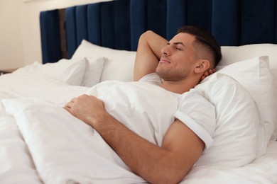 Handsome man sleeping in comfortable hotel bed