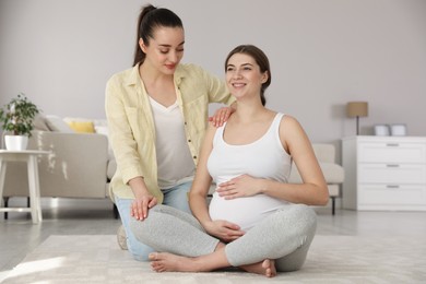 Doula working with pregnant woman in living room. Preparation for child birth