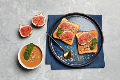 Tasty toasts served with fig, peanut butter and walnuts on light grey marble table, flat lay