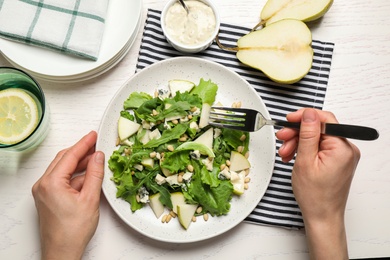Woman with tasty pear salad at white table, top view