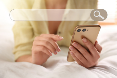 Search bar of internet browser and woman using smartphone on bed at home, closeup